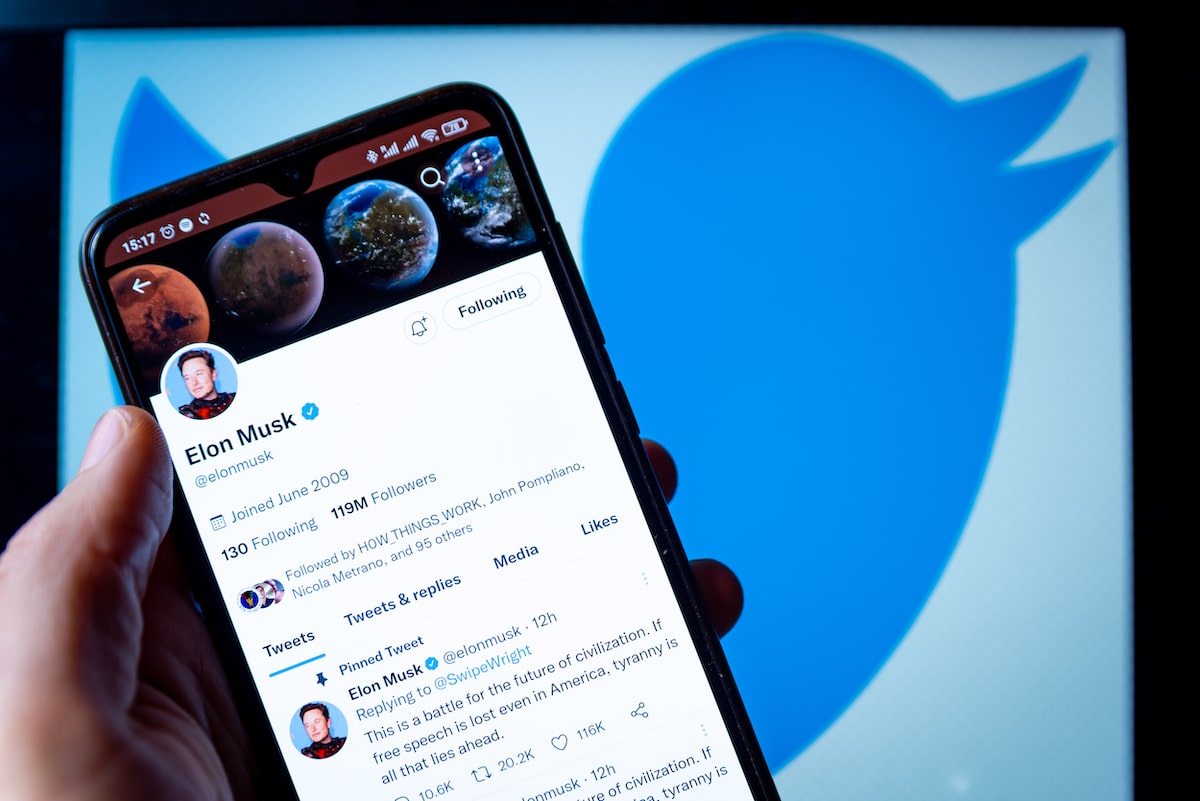 Elon Musk's Twitter page displayed on a smartphone with the Twitter logo in the background