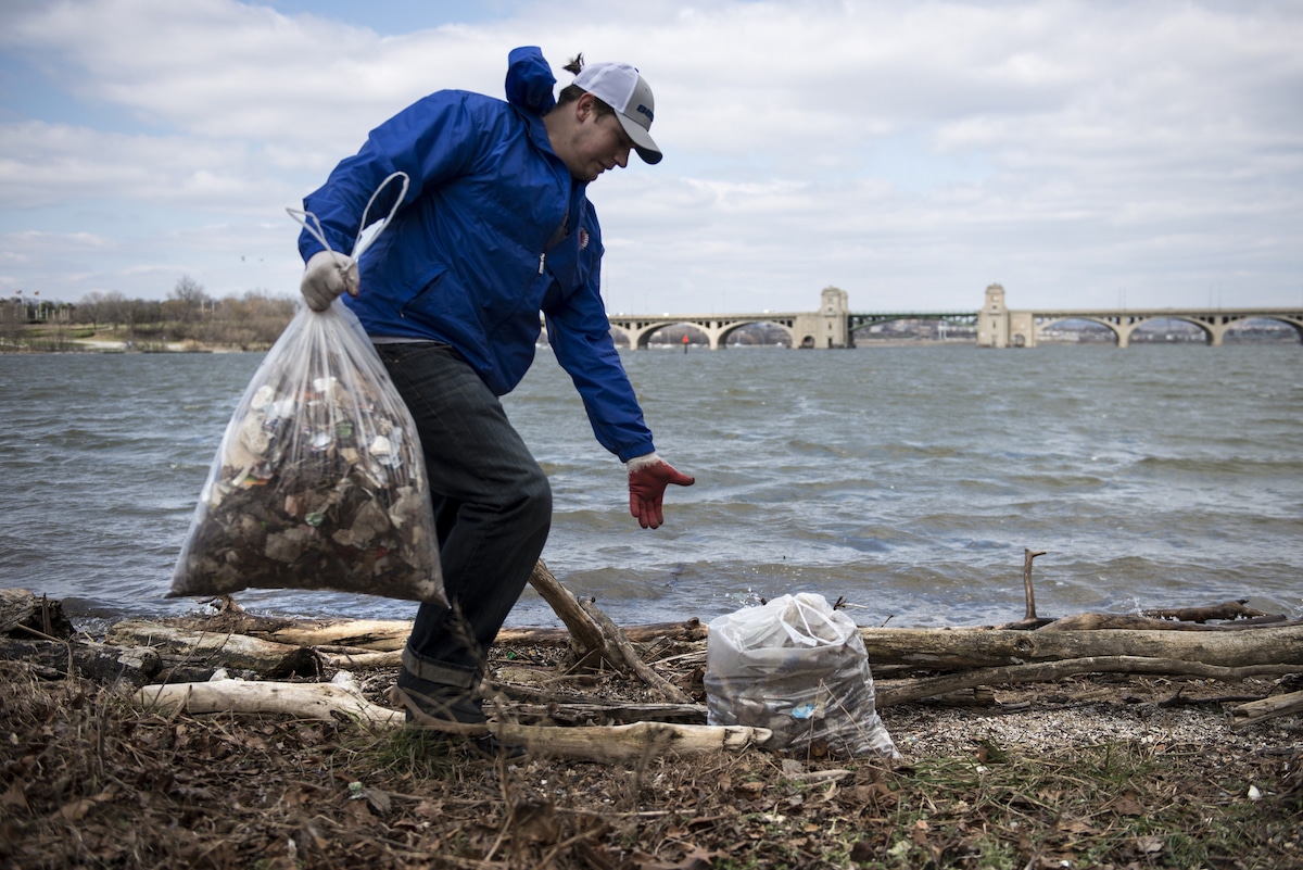 A volunteer collects litter along a Baltimore waterway