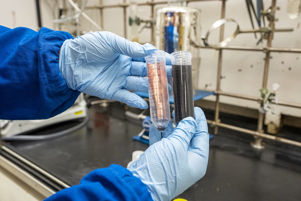 A Berkely Lab scientist holds vials dissolving batteries using the Quick-Release Binder
