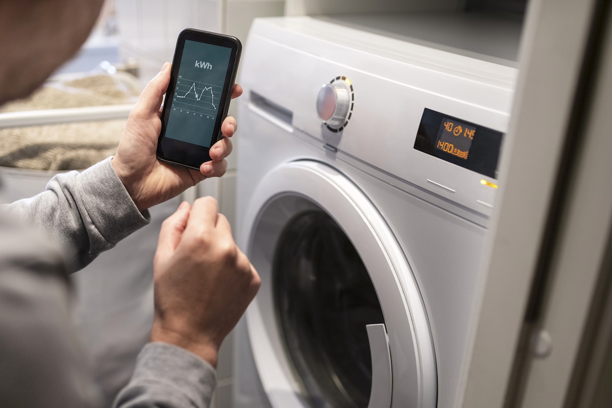 A person checks the energy use of a washing machine, using a smartphone
