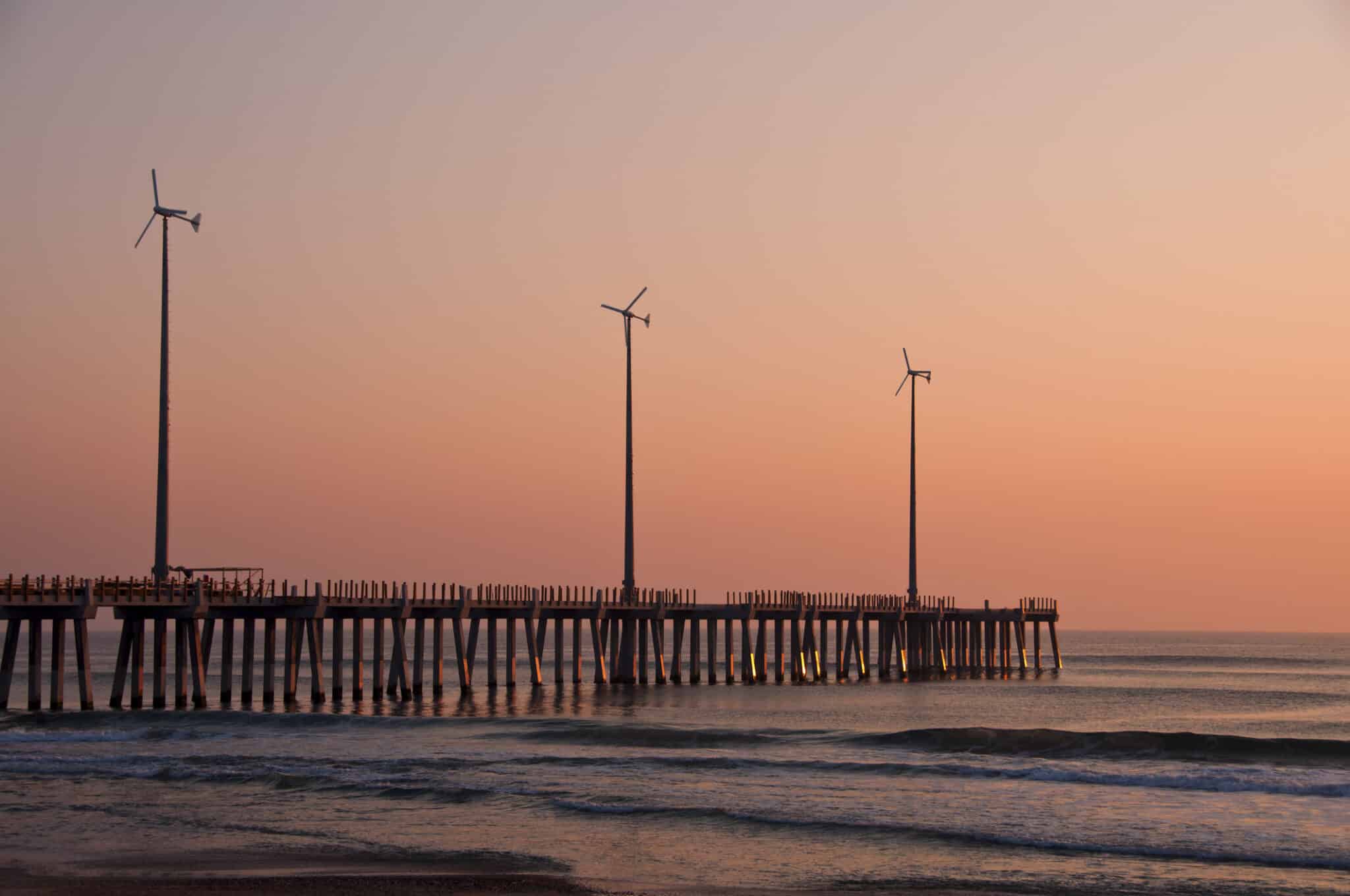 USA, North Carolina, Outer Banks, Kill Devil Hills, pier with wind turbines at sunset