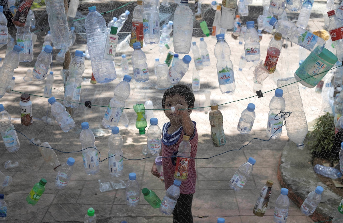 A boy views an installation made of plastic bottles as part of a campaign to save the beach from plastics pollution in Indonesia