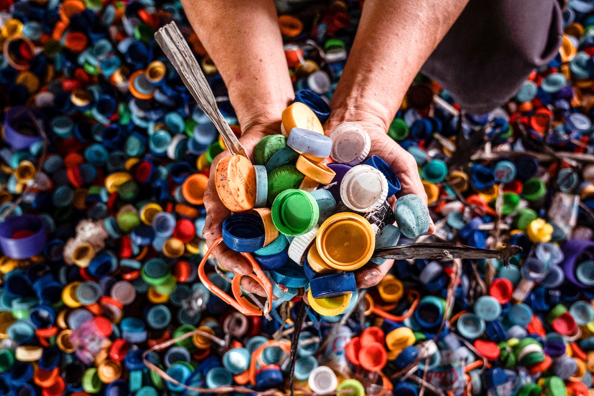 A worker gathers bottle caps to sell to plastic recycling factories in Indonesia