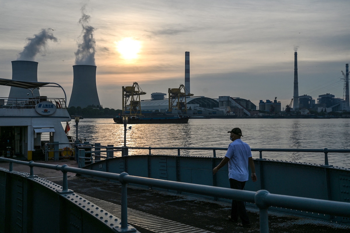 A man walks towards a ferry with the Wujing coal-electricity power station across the Huangpu River in the Minhang district of Shanghai, China