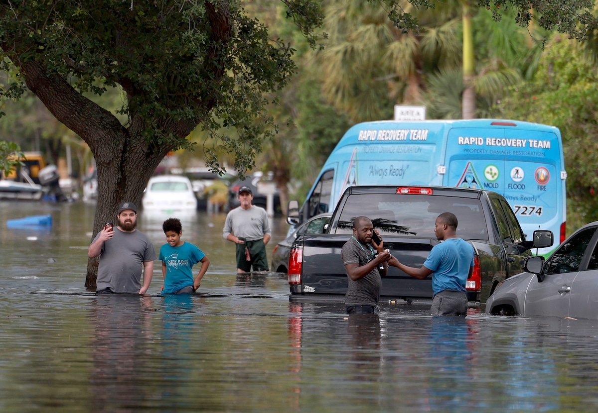 People walk through a flooded neighborhood in Fort Lauderdale, Florida