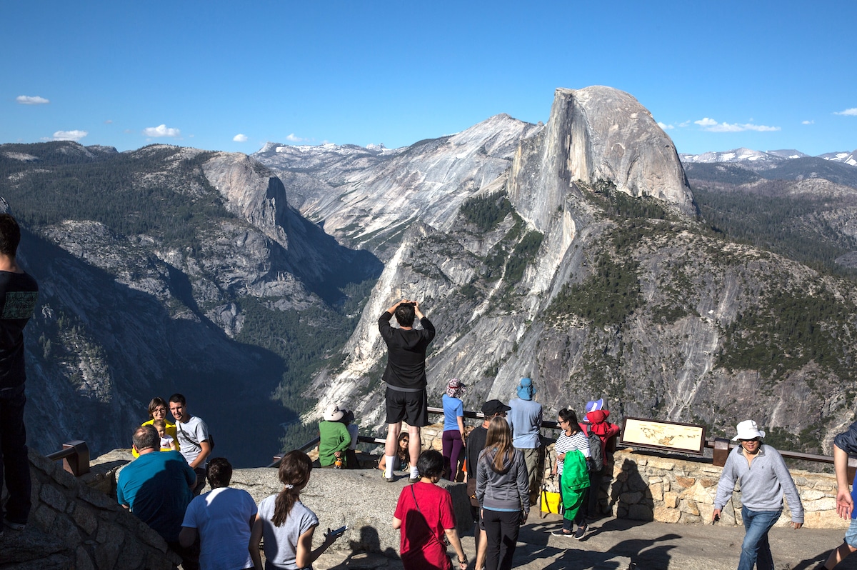 Yosemite National Park summer visitors take pictures at Glacier Point with a view of Half Dome