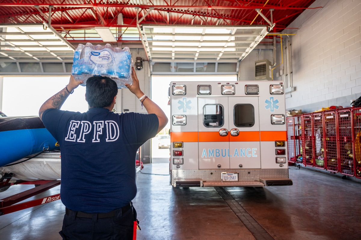 An emergency medical technician with the Eagle Pass Fire Department helps stock an ambulance with water and ice during a dangerous heatwave in Eagle Pass, Texas
