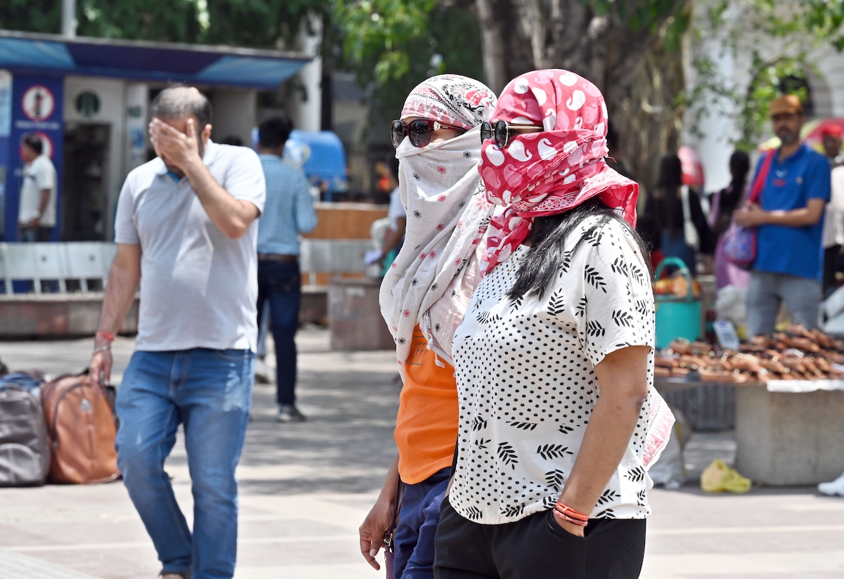 People outside with head coverings for protection during a heat wave at Connaught Place, New Delhi, India