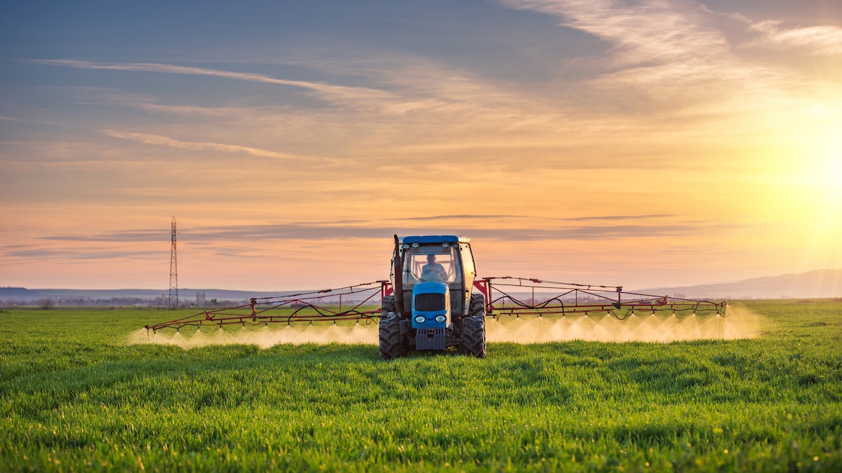 A tractor sprays herbicides on a field of crops