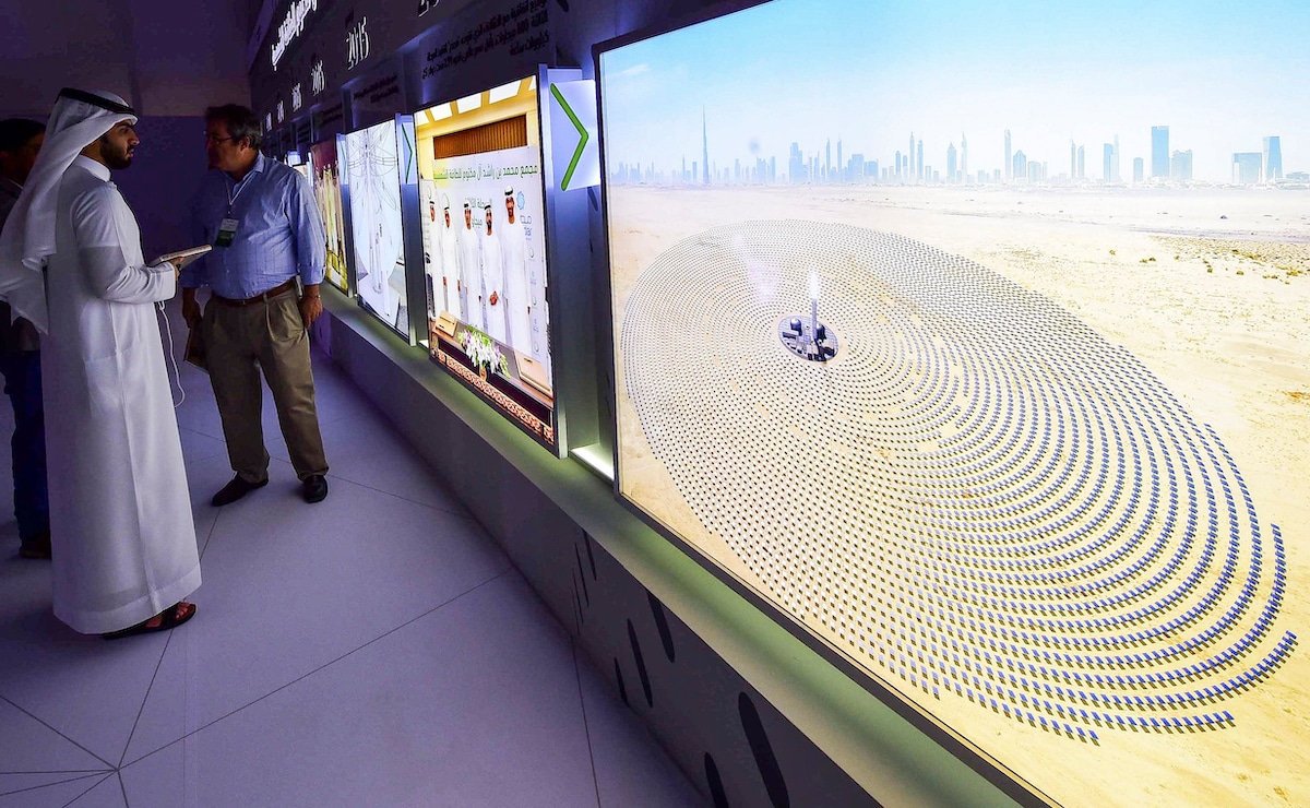 Visitors look at screens displaying images of the Mohammed bin Rashid Al-Maktoum Solar Park at the solar plant in Dubai, United Arab Emirates