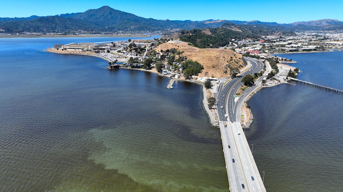 Cars drive on the Richmond-San Rafael Bridge over brownish water from an algal bloom in the San Francisco Bay in San Rafael, California