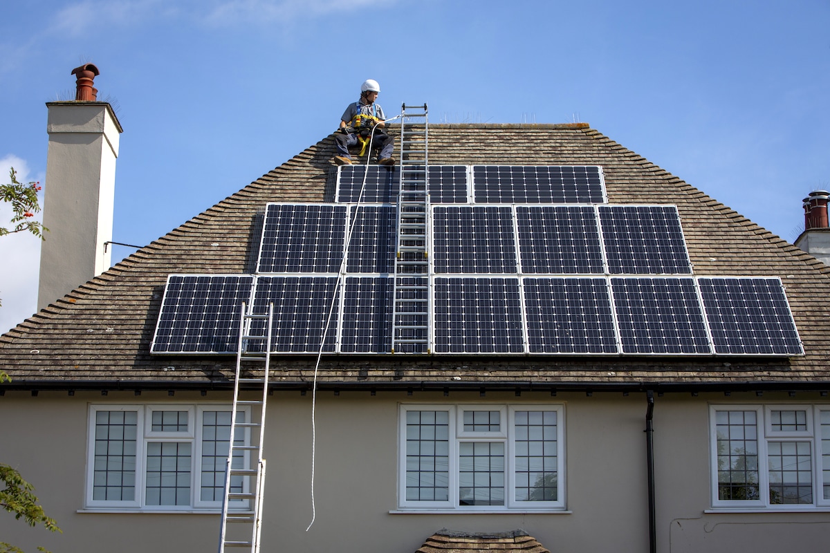 A maintenance person works on a residential rooftop solar array in Folkestone, Kent, UK