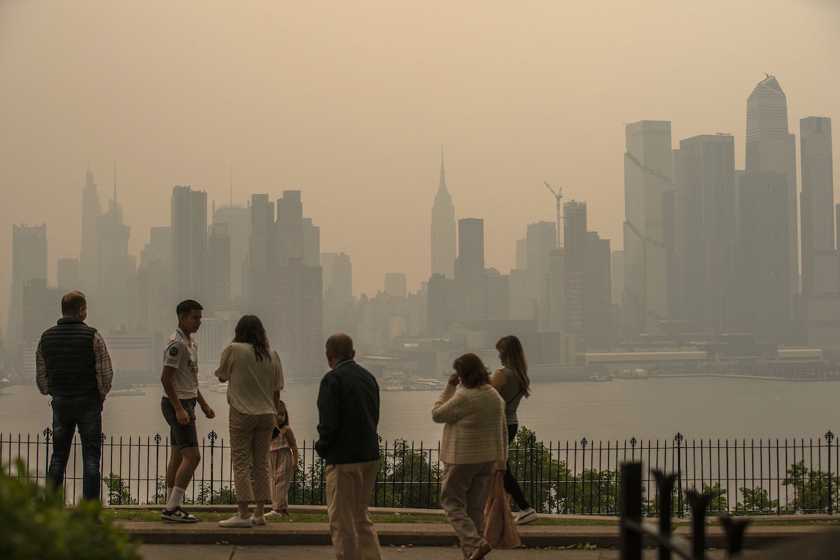 People stand in a park in Weehawken, New Jersey as the New York City skyline is covered with smoke from Canada wildfires