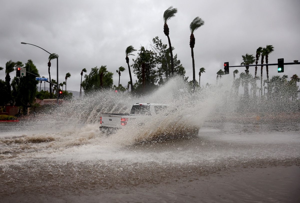A vehicle drives through a flooded street from Tropical Storm Hilary in Cathedral City, California