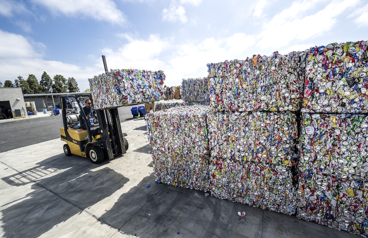 A recycling technician loads an 800-pound block of compressed aluminum cans at OCC Recycling Center in Costa Mesa, California