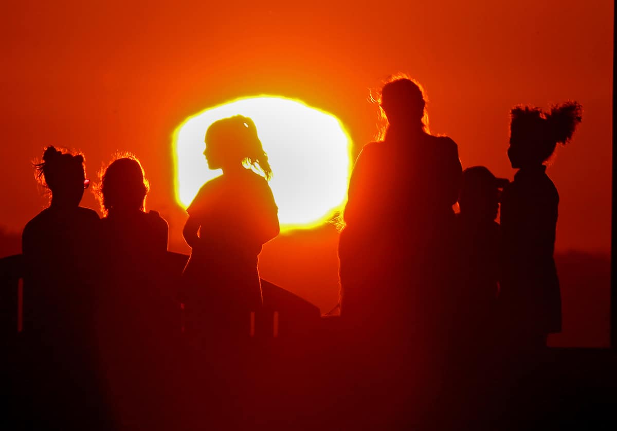 The sun silhouettes visitors to Signal Hill after another hot day in Long Beach, California
