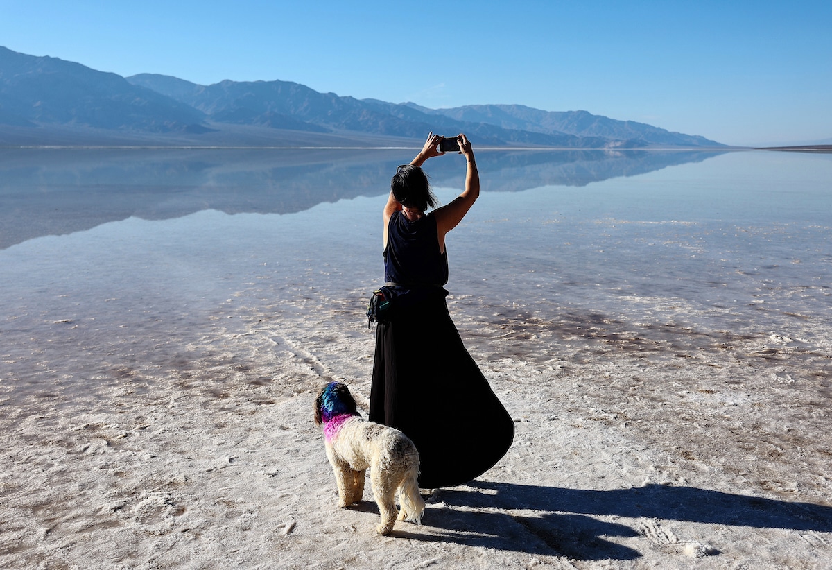A visitor to Death Valley National Park takes a photo with her dog at the sprawling temporary lake at Badwater Basin salt flats