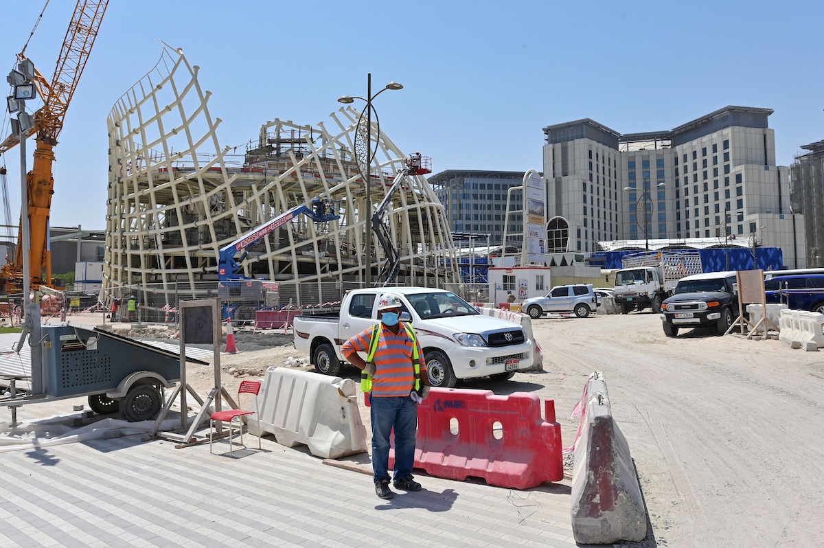 A migrant worker stands in front of the Dubai Expo 2020 site, under construction in October 2021 and currently being adapted for COP28 in November