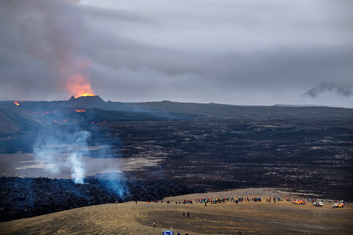 Volcanic activity from Iceland’s Fagradalsfjall volcano in July while many tourists in the distance watch the flames