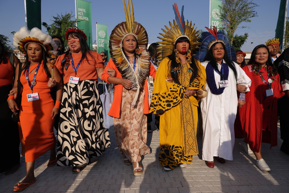 Representatives of indigenous groups from Brazil march and sing through the conference venue on day six of COP28 in Dubai