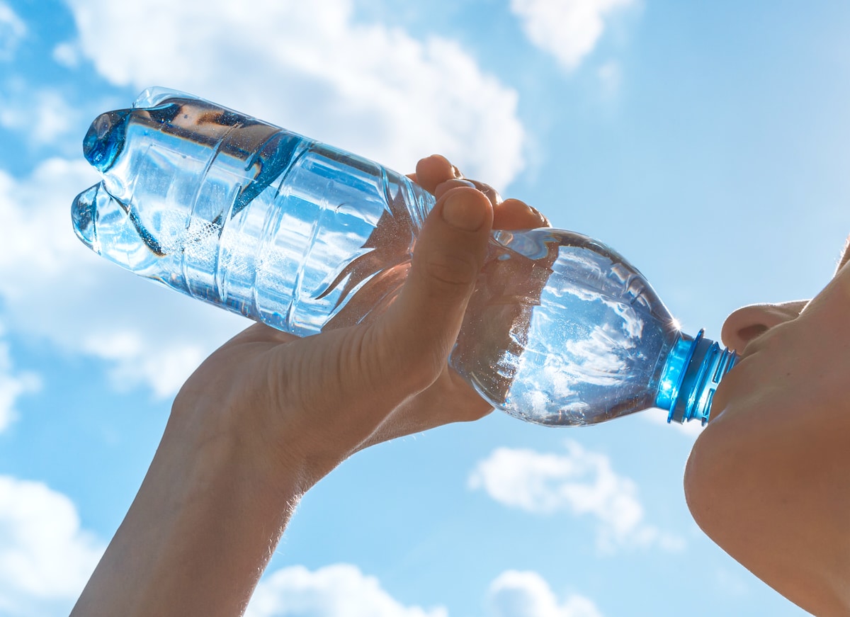 Closeup of an athlete drinking water from a plastic bottle after a workout. A new study measured plastic fragments in bottled drinking water