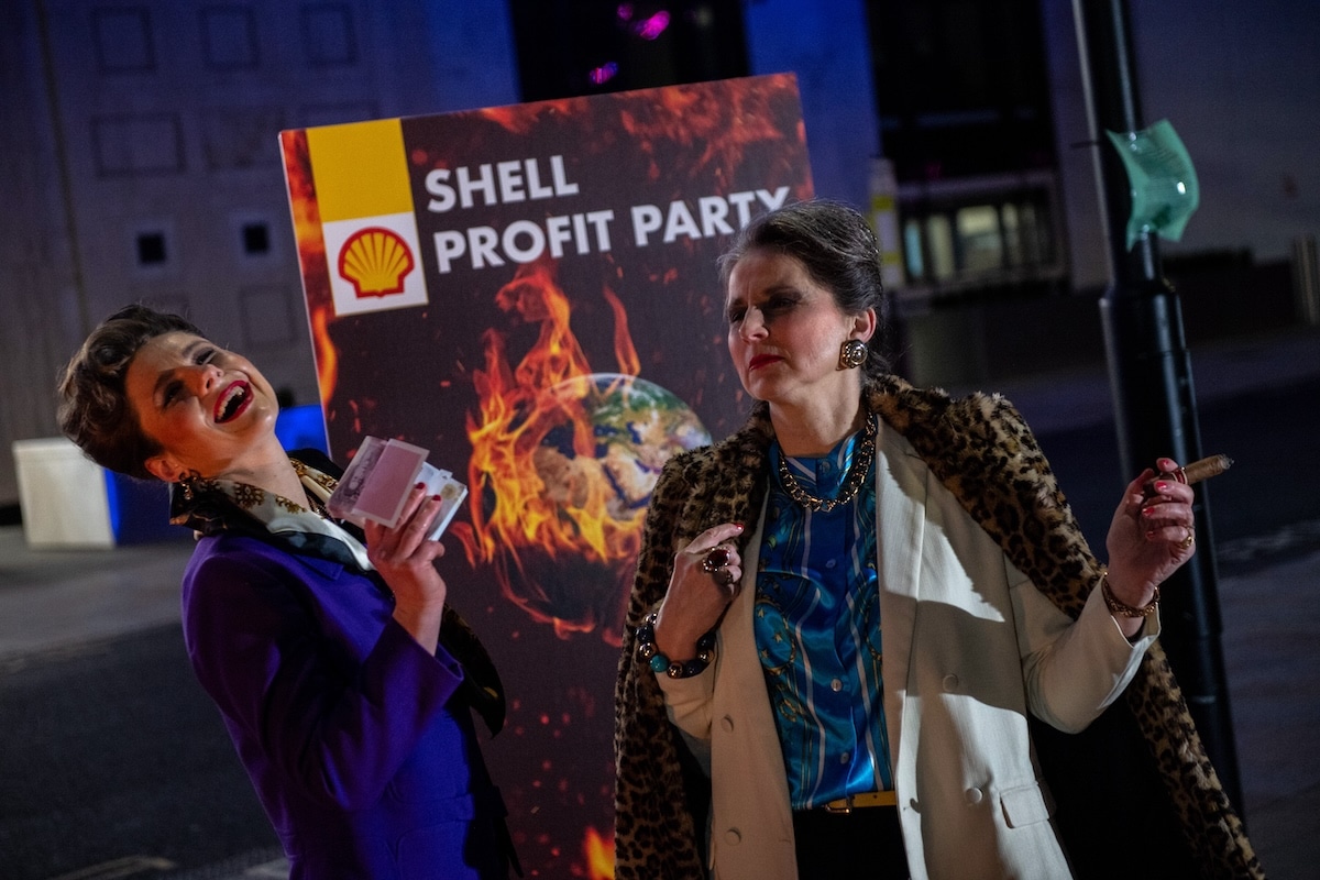 Greenpeace climate activists hold a mock Shell profits party behind a burning sign reading "Your Future" during a protest outside Shell's headquarters in London, England