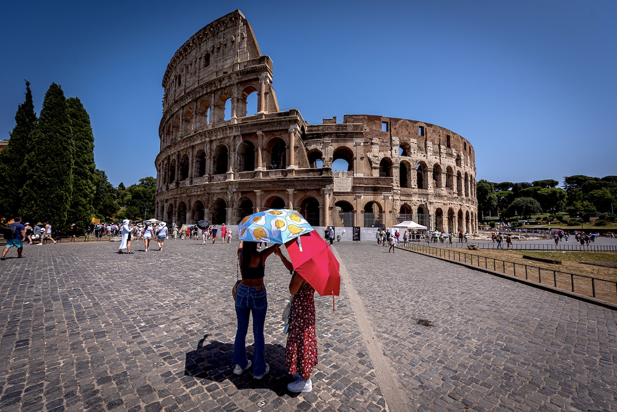 Tourists hold umbrellas to protect themselves from the sun near the Colosseum during a long heat wave with temperatures reaching 113°F and feeling hotter in Rome, Italy