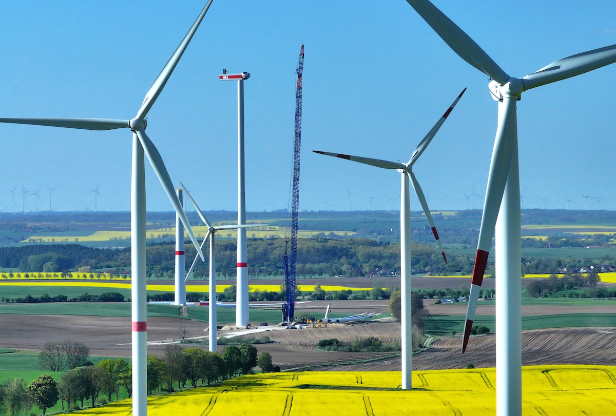 Wind turbines spin as two others stand under construction at a wind park near Pinnow, Germany